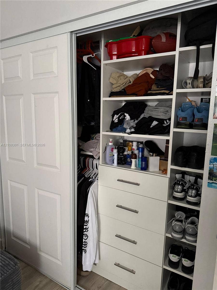 7680 SW 153rd Court, #204, Miami, Miami, FL 33193 Closet featuring sliding six-panel doors, integrated white shelving, built-in drawer stack with metallic pulls, and dedicated vertical shoe storage