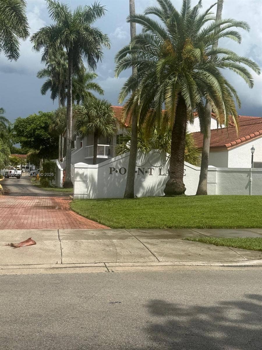 7680 SW 153rd Court, #204, Miami, Miami, FL 33193 Stucco monument signage featuring mature palm trees, tile roof structures, and paved brick driveway