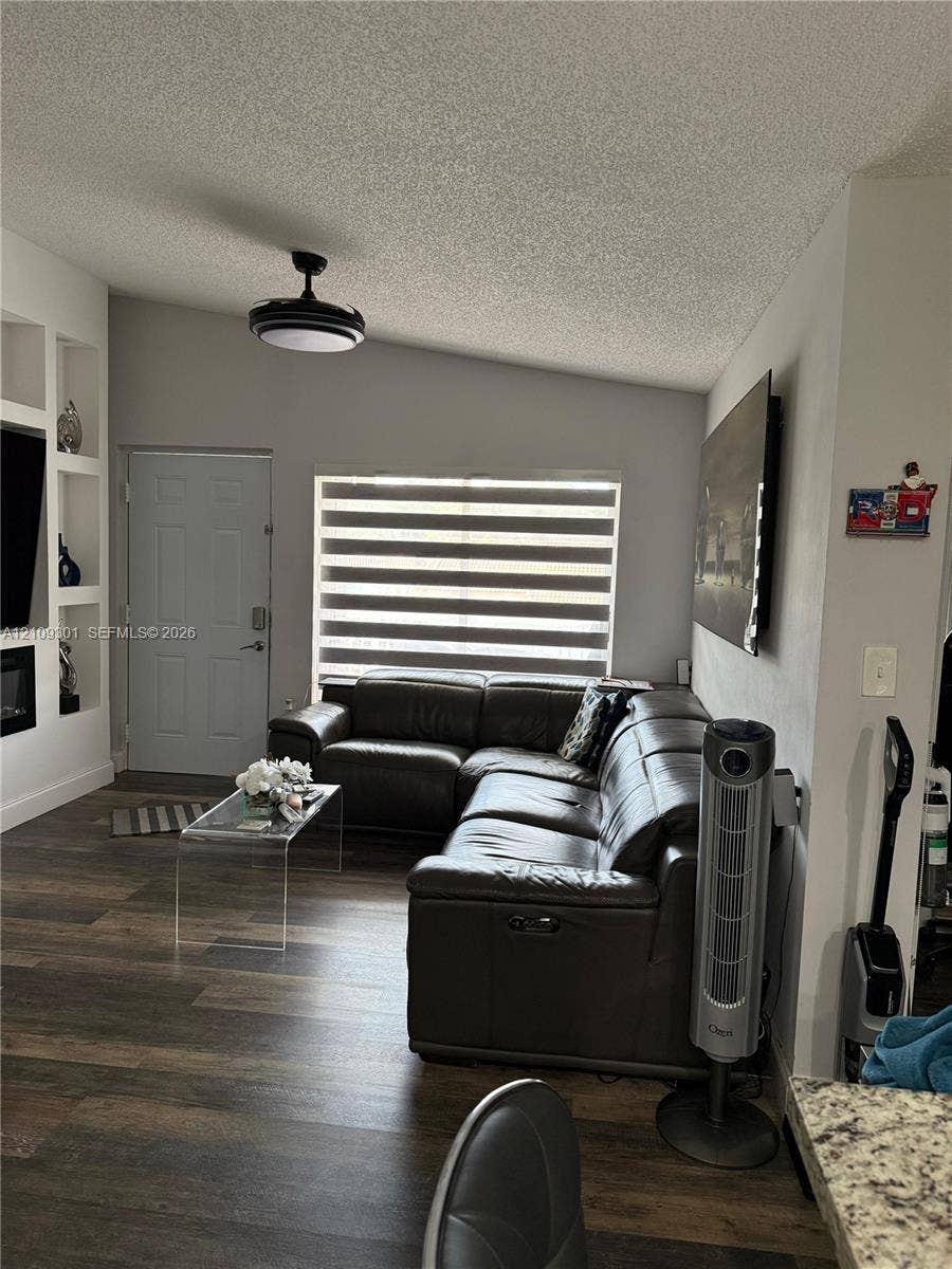 7680 SW 153rd Court, #204, Miami, Miami, FL 33193 Living area featuring wood-finish flooring, vaulted ceilings, built-in shelving, and a modern ceiling fan with integrated lighting