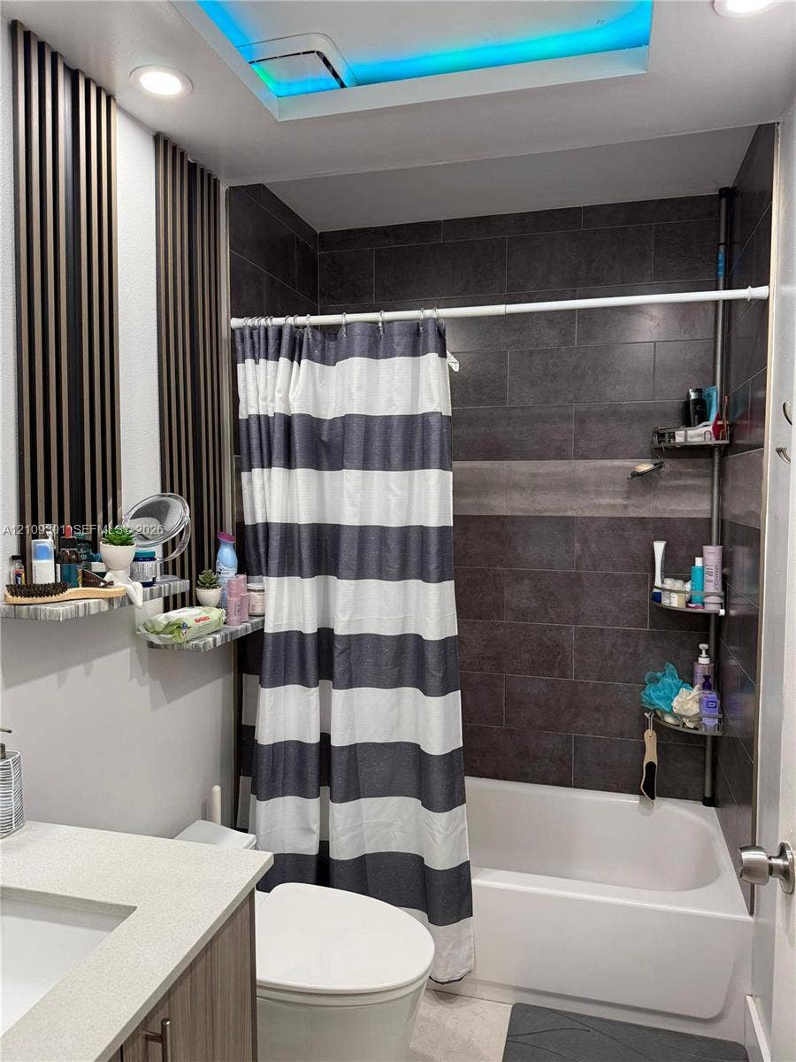 7680 SW 153rd Court, #204, Miami, Miami, FL 33193 Bathroom featuring large-format dark charcoal tile shower surround, integrated LED ceiling lighting, vertical slat wall accents, and vanity with solid-surface countertop