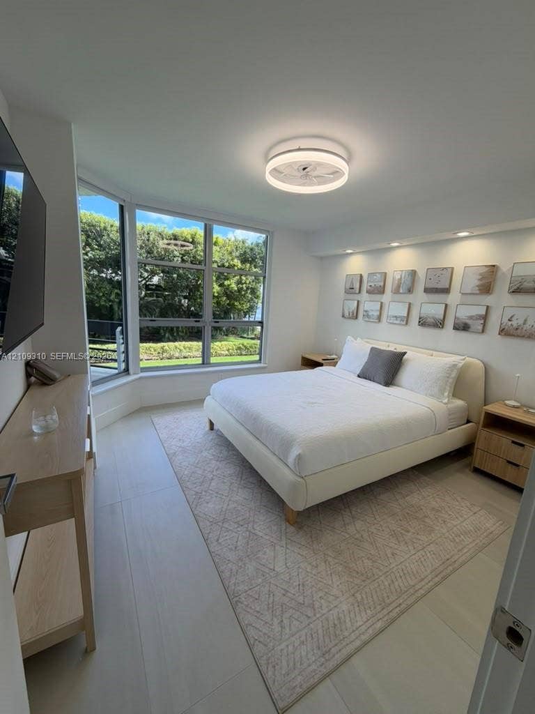 Large bay windows, recessed ceiling lighting, circular modern ceiling fixture, and light-toned flooring