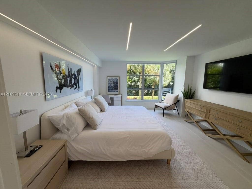 Neutral-toned room featuring expansive floor-to-ceiling windows, modern recessed linear ceiling lighting, wall-integrated cove lighting, and light-toned flooring