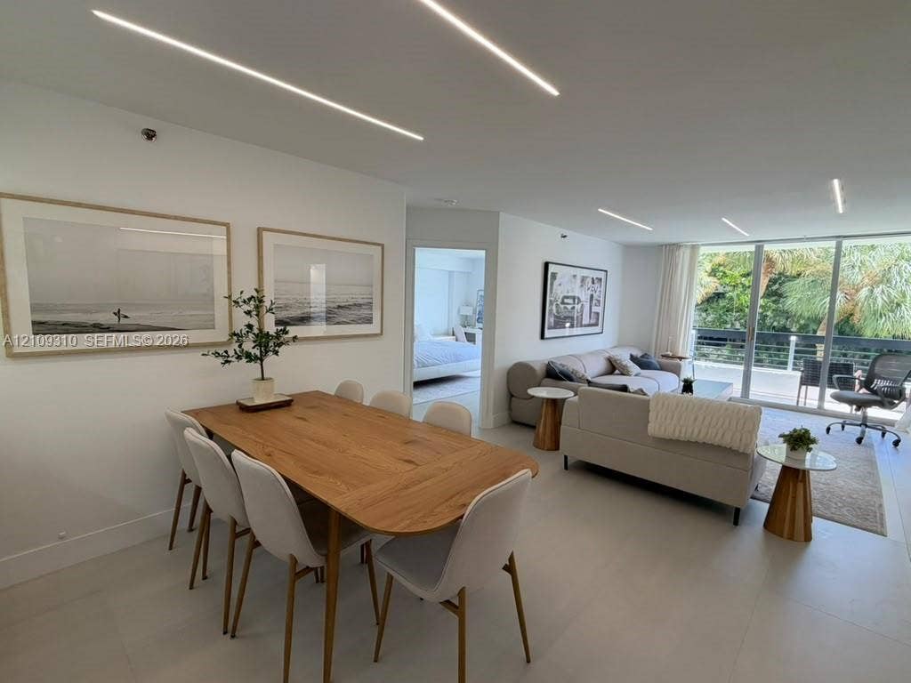 Open-concept interior featuring linear recessed lighting, large-format tile flooring, and floor-to-ceiling glass sliding doors