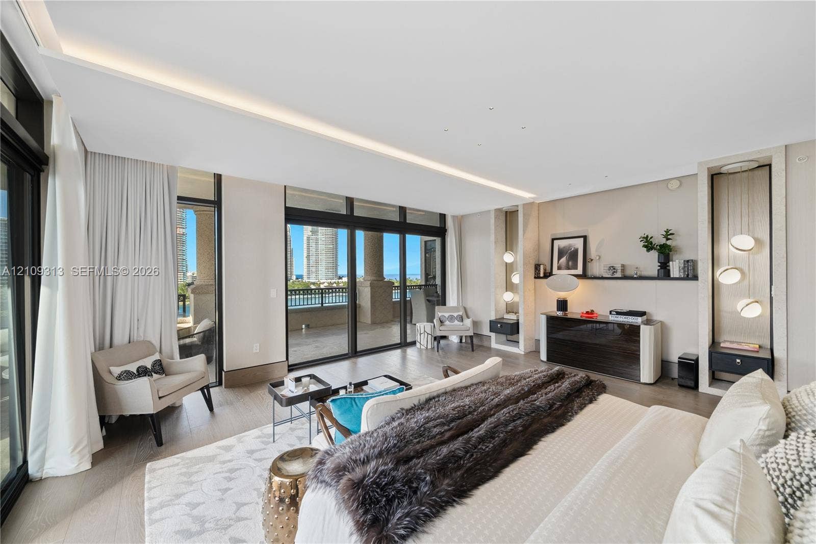 Floor-to-ceiling sliding glass doors, built-in recessed shelving with integrated accent lighting, light-toned wood-finish flooring, and a covered balcony