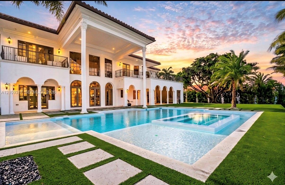 Classical estate exterior featuring multi-story arched porticos, decorative columns, integrated swimming pool with a raised spa, and manicured landscaping with stone pavers