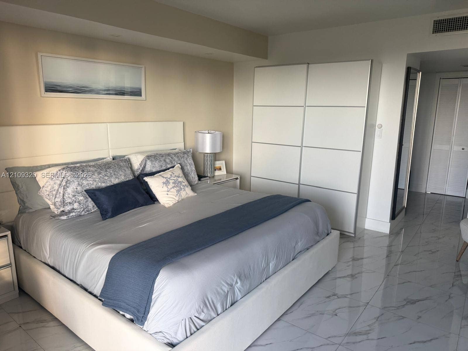 Polished stone-finish flooring with a marbleized pattern, floor-to-ceiling multi-panel wardrobe, and recessed lighting