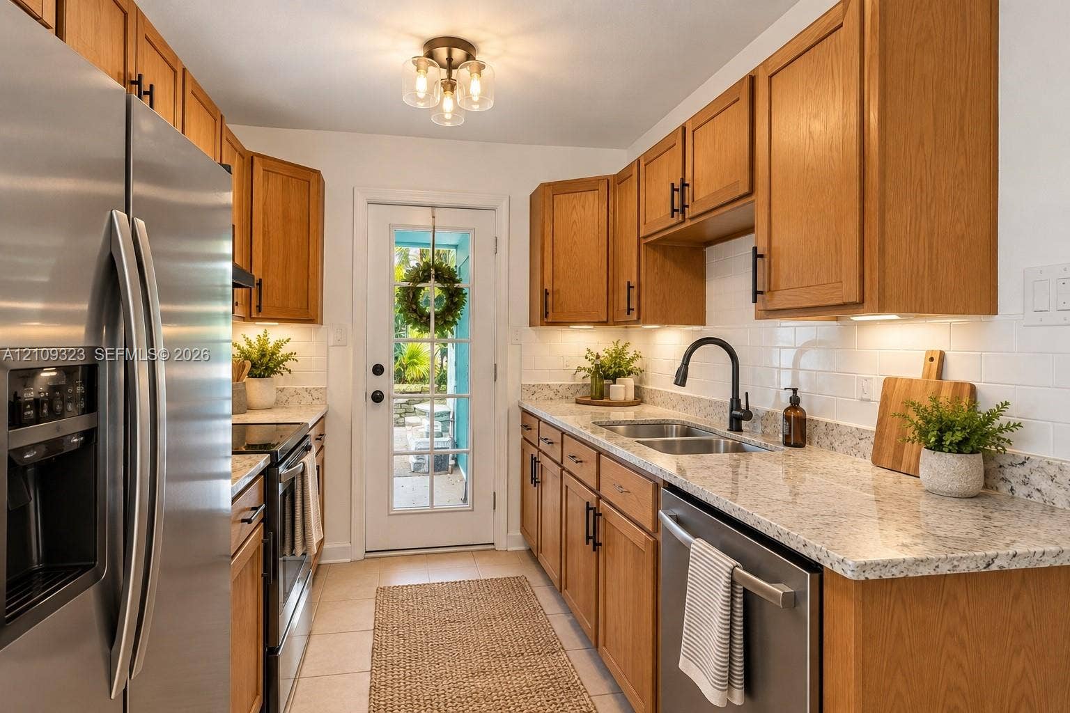 911 Shady Park Terrace, Daytona Beach, FL 32117 Kitchen featuring wood cabinetry, stone countertops, stainless steel appliances, white subway tile backsplash, and a glass-paneled exterior door