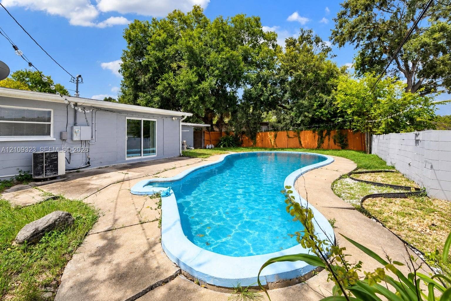 911 Shady Park Terrace, Daytona Beach, FL 32117 Backyard featuring a free-form swimming pool, concrete patio, wood privacy fencing, and masonry perimeter wall