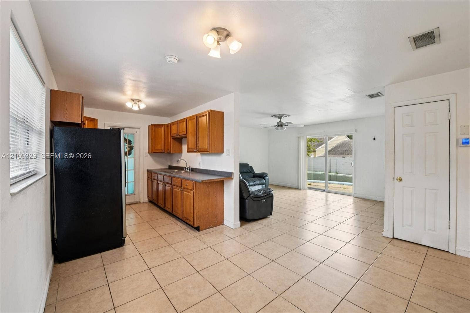 911 Shady Park Terrace, Daytona Beach, FL 32117 Kitchen featuring wood cabinetry, solid-surface countertops, tile flooring, dual-light ceiling fixtures, and glass-paneled sliding doors
