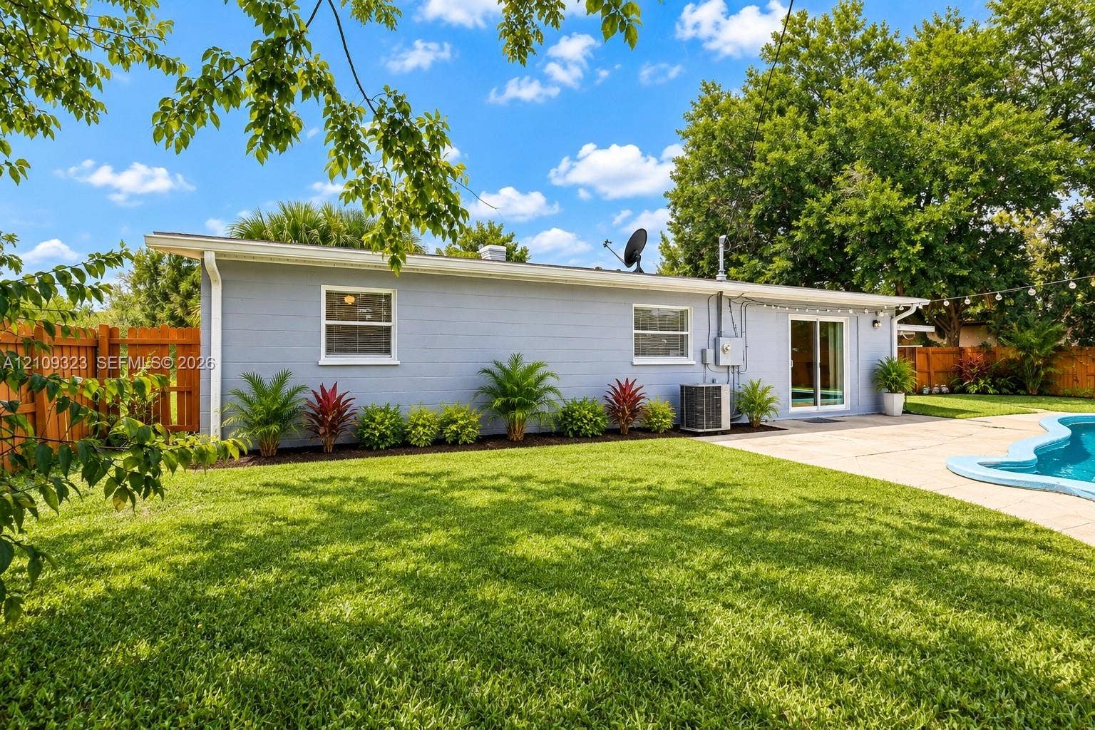 911 Shady Park Terrace, Daytona Beach, FL 32117 Expansive backyard featuring a swimming pool, concrete patio, perimeter wood fencing, and mature landscaping