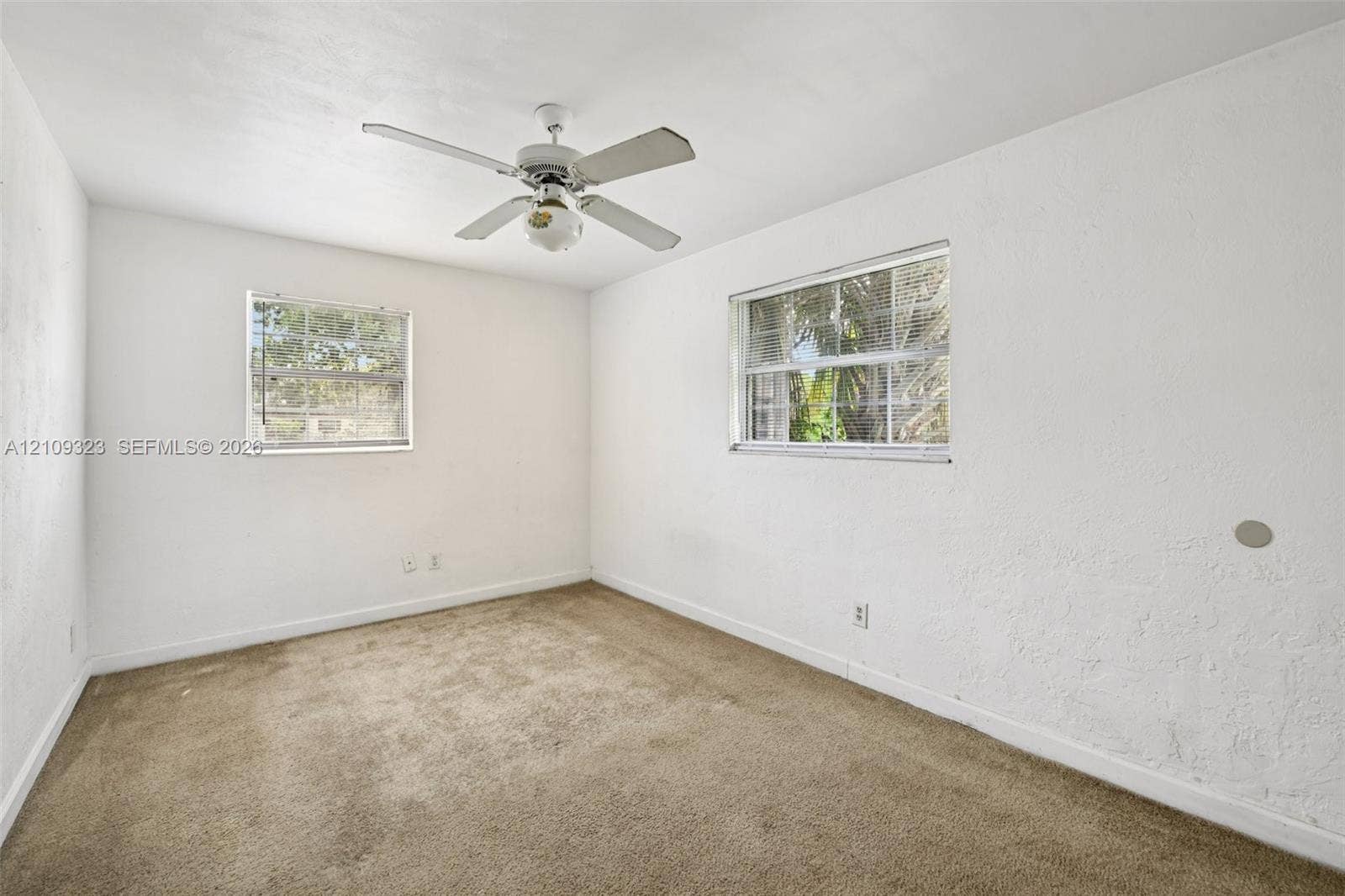 911 Shady Park Terrace, Daytona Beach, FL 32117 Interior space featuring neutral wall-to-wall carpeting, white textured walls, two windows with multi-pane glass, and a ceiling-mounted fan with integrated lighting