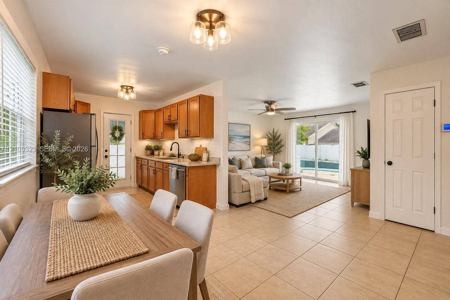 911 Shady Park Terrace, Daytona Beach, FL 32117 Kitchen featuring medium-toned wood cabinetry, stone countertops, stainless steel appliances, neutral tile flooring, and sliding glass doors