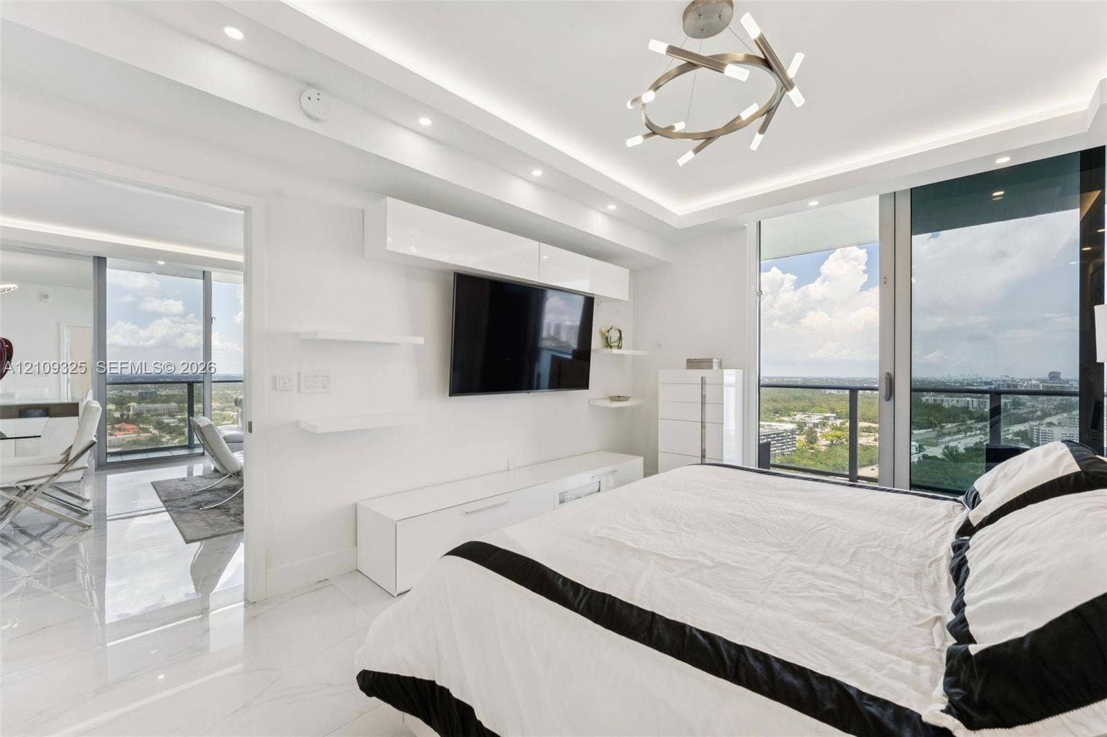 Floor-to-ceiling glass windows, recessed ceiling lighting with crown molding, custom built-in cabinetry, polished stone-finish flooring, and modern geometric chandelier