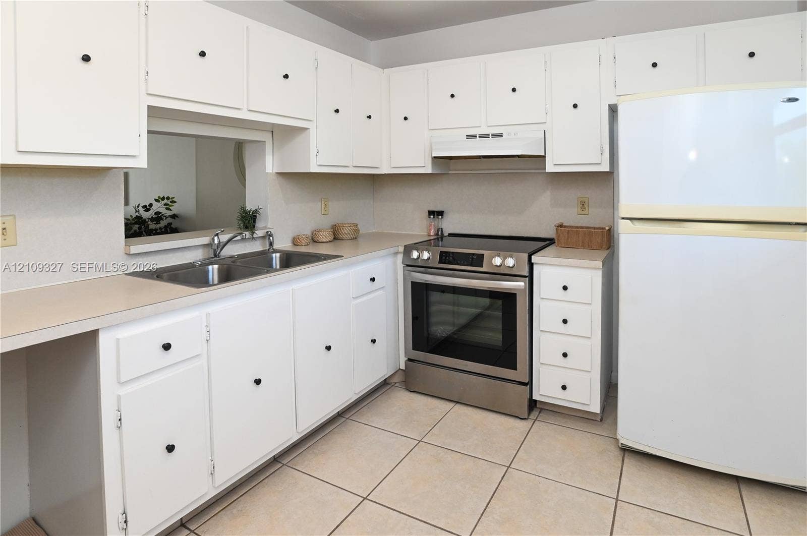 Kitchen featuring white cabinetry, stainless steel range, dual-basin sink, laminate countertops, and tile flooring