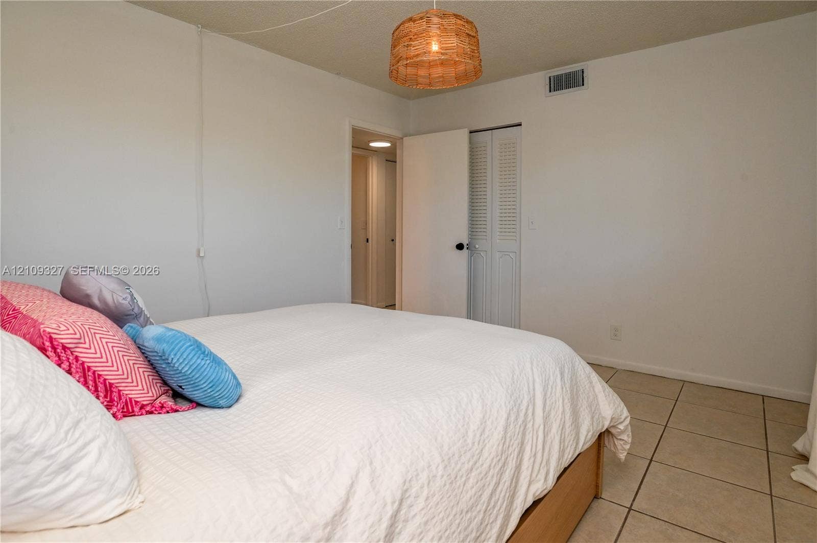 Ceramic tile flooring, louvered bi-fold closet doors, and woven drum pendant lighting