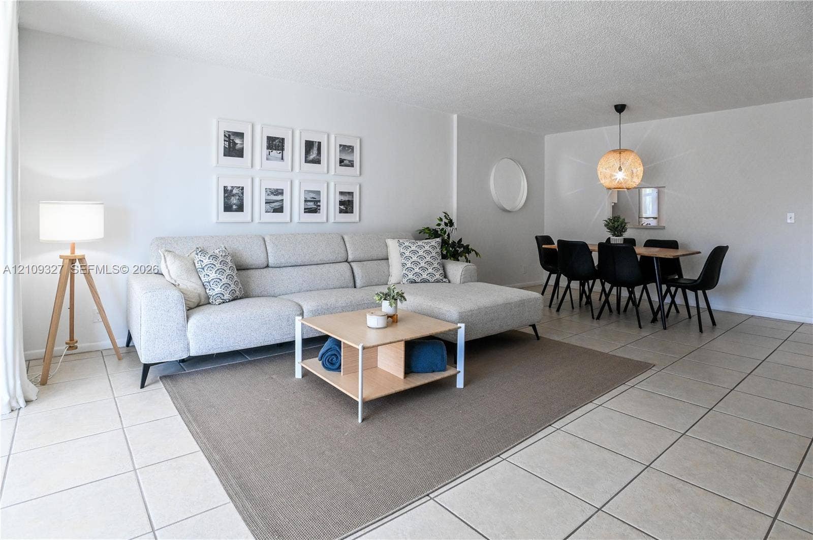 Neutral-toned ceramic tile flooring, rounded wall mirror, and woven pendant light fixture