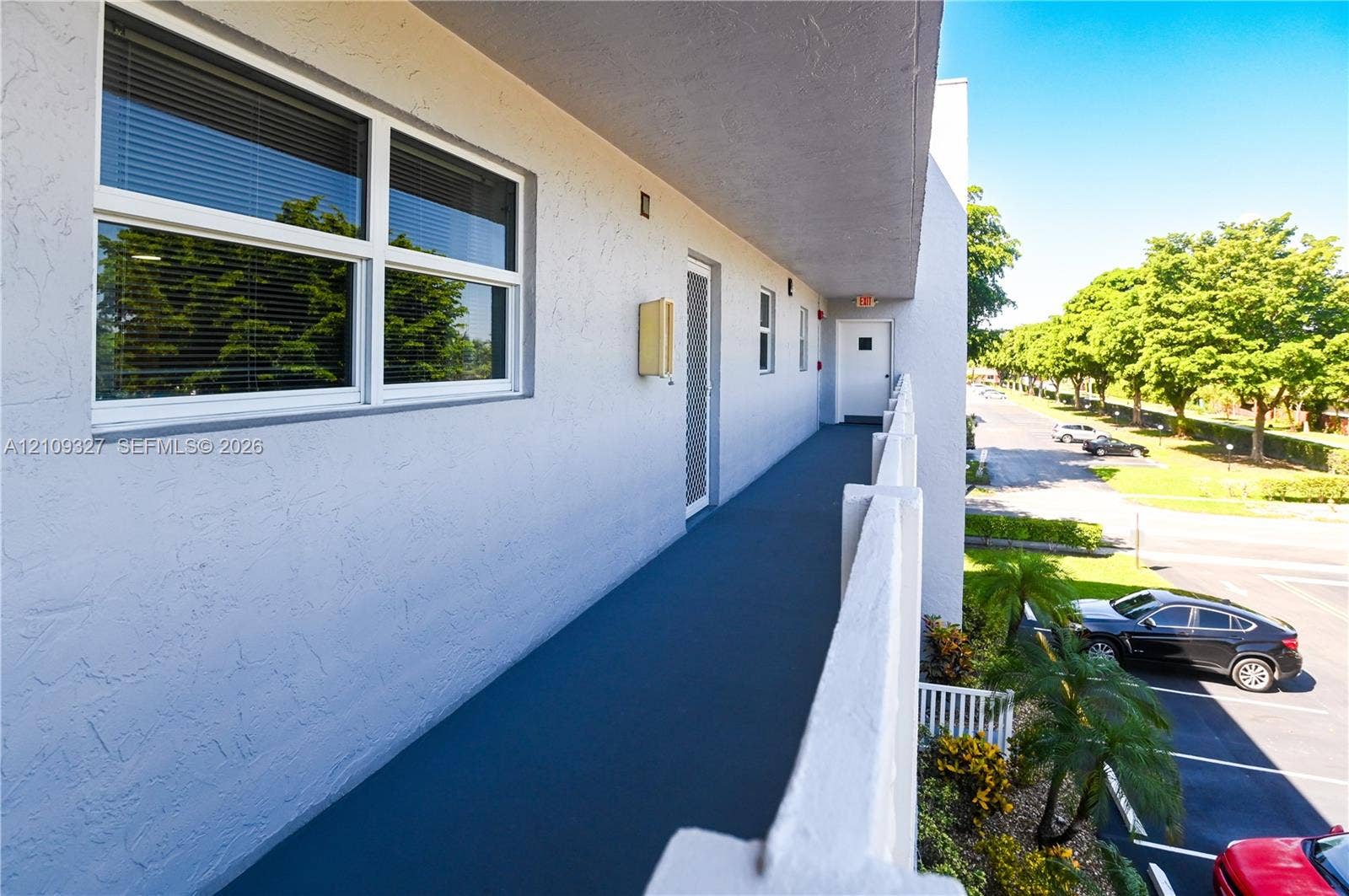 Exterior walkway featuring a painted concrete floor, stucco wall finish