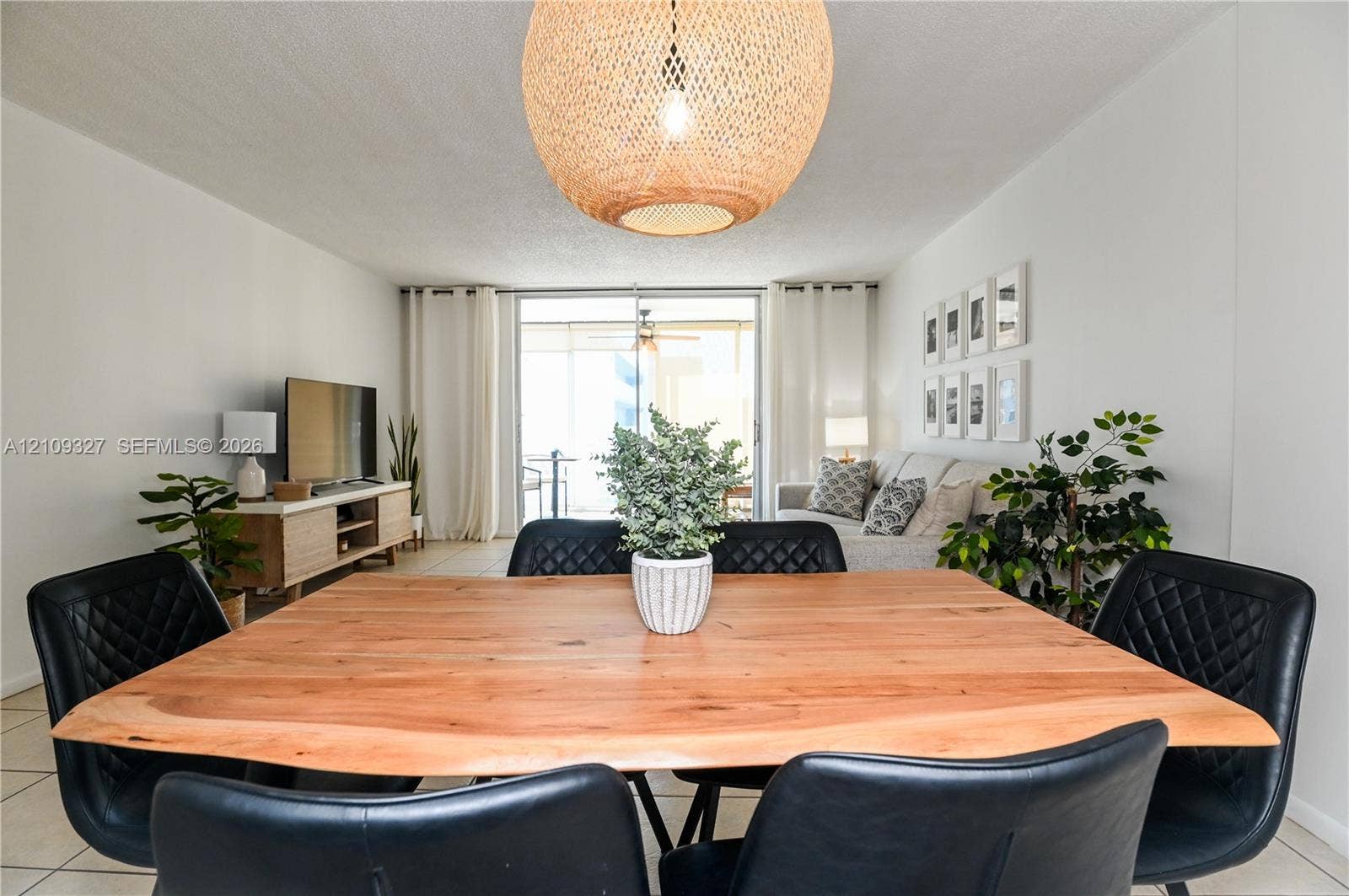 Large woven dome light fixture, sliding glass doors, and neutral tile flooring