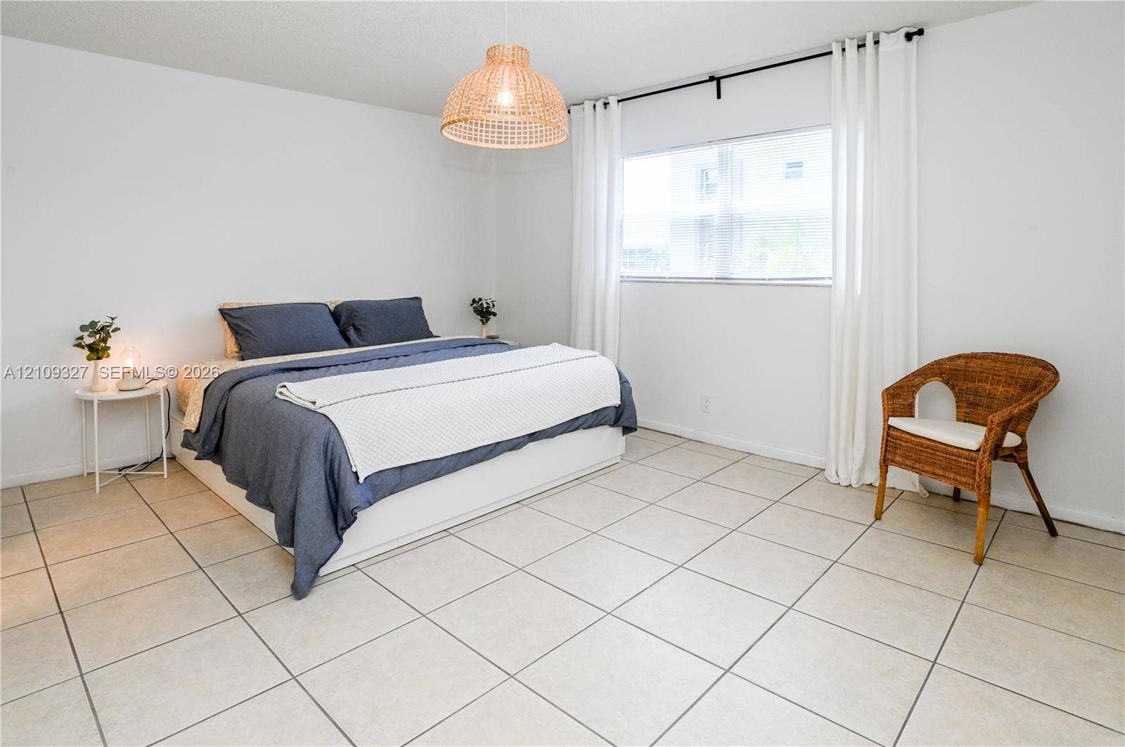 Neutral-toned ceramic tile flooring, woven basket-style pendant lighting, and a window with curtains