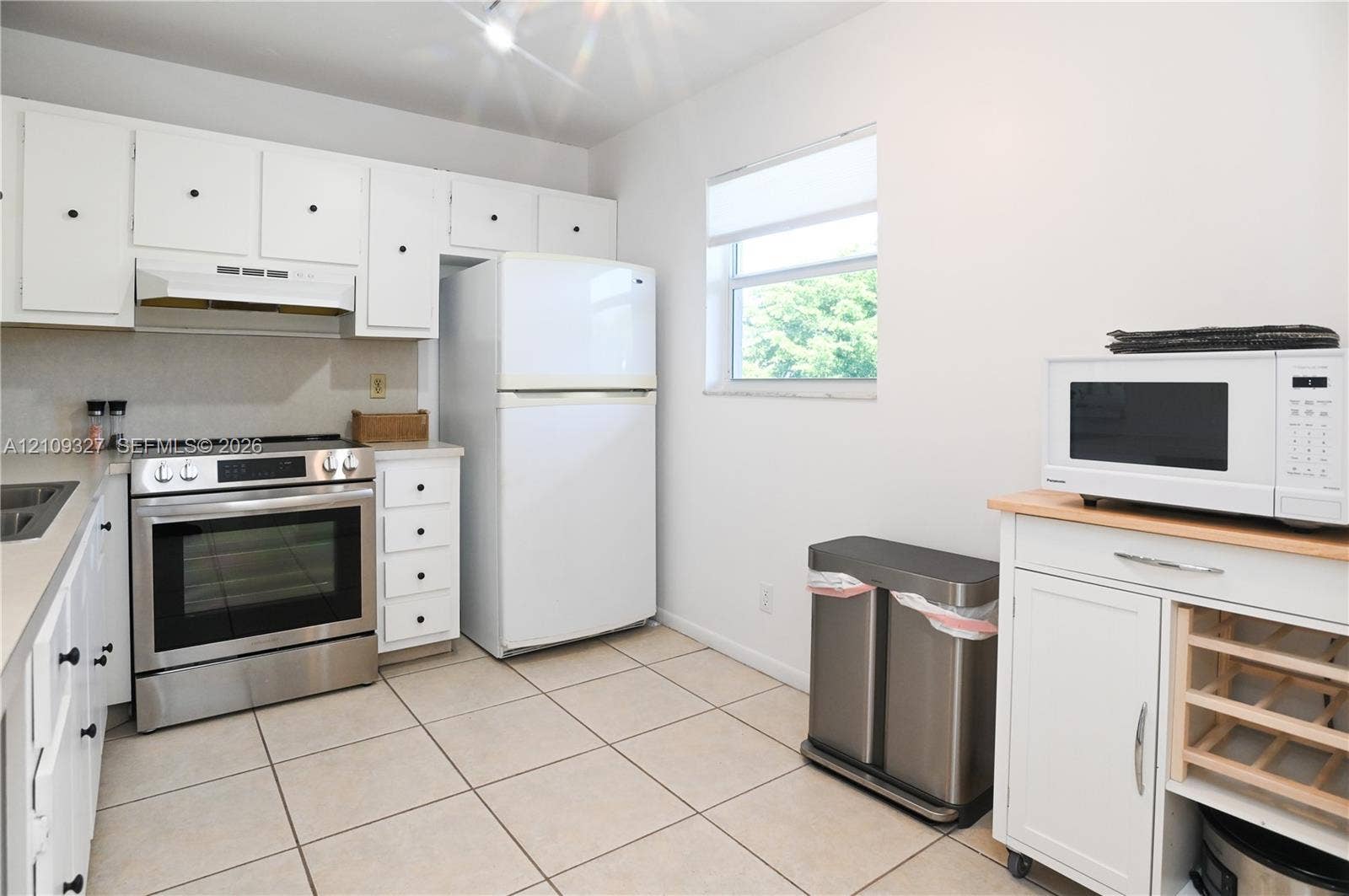Kitchen featuring white cabinetry, stainless steel range, tile flooring, and neutral solid-surface countertops