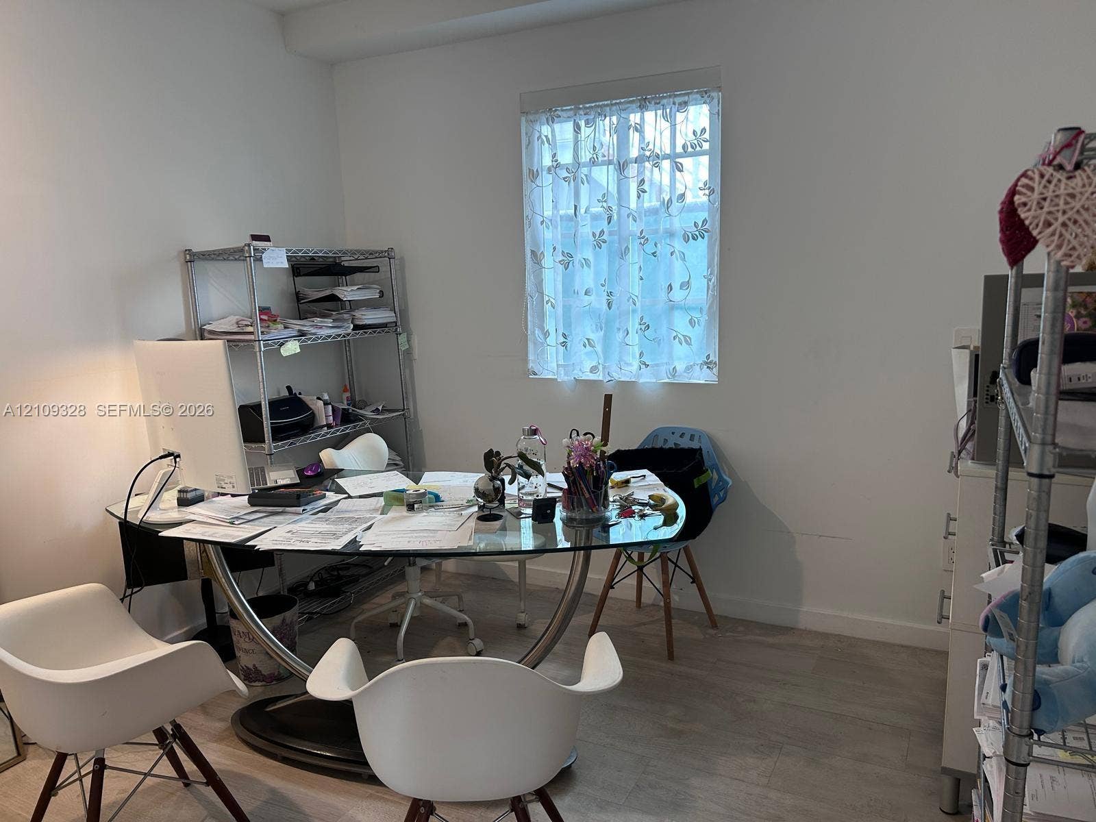 Neutral-toned interior space featuring light-colored wood-finish flooring and a single-pane window