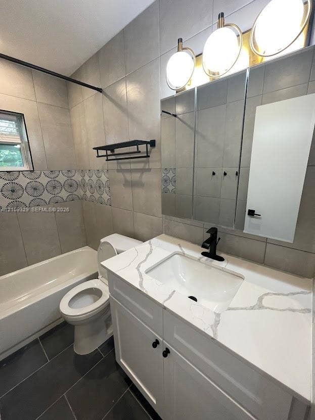 2418 Polk Street, #205, Hollywood, Hollywood, FL 33020 White cabinetry vanity with a stone-composite countertop, matte black faucet, wall-mounted medicine cabinet with integrated lighting, and decorative tile accent wall