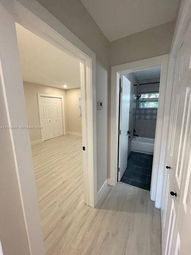 2418 Polk Street, #205, Hollywood, Hollywood, FL 33020 Wood-finish flooring throughout, light-toned interior walls, dual-panel interior doors, and a bathroom featuring dark-toned floor tiling and decorative tile wall accents