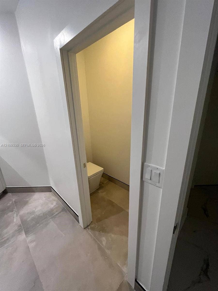 Enclosed water closet featuring large-format stone-finish floor tile and a contemporary dual-flush toilet