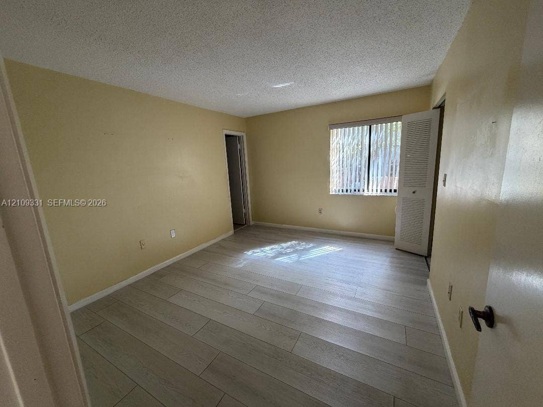 10231 Fontainebleau Boulevard, #106, Miami, FL 33172 Interior space featuring wood-finish tile flooring, a window with vertical blinds, and a built-in closet with louvered doors
