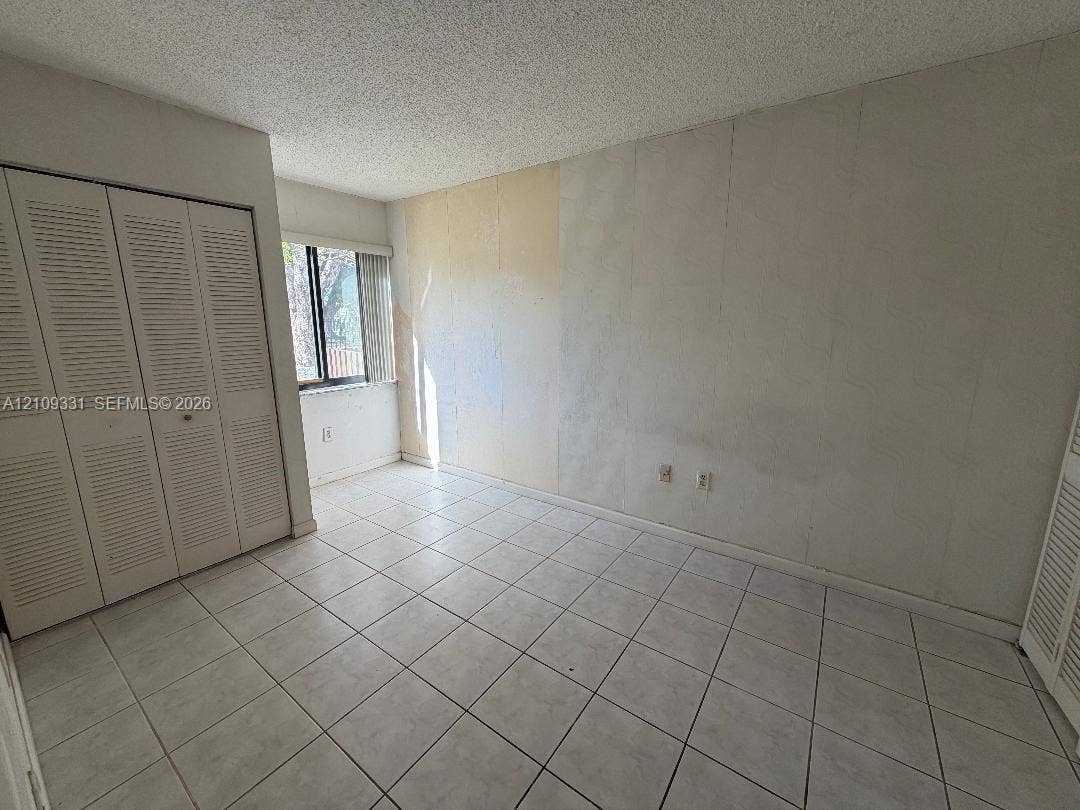 10231 Fontainebleau Boulevard, #106, Miami, FL 33172 Room featuring white tile flooring, dual louvered-door closets, and a window with vertical blinds