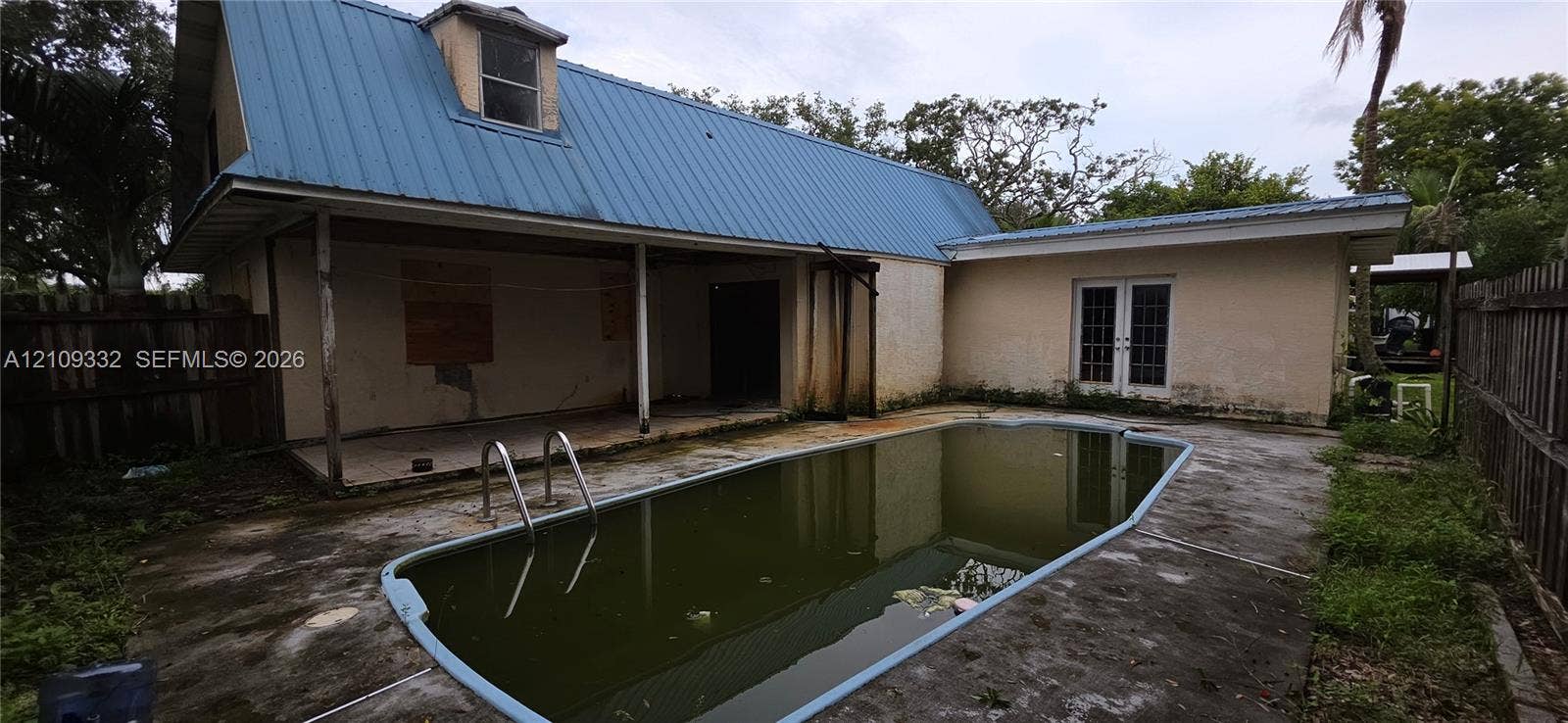 In-ground swimming pool with metal ladder, exterior covered patio, and metal roof system