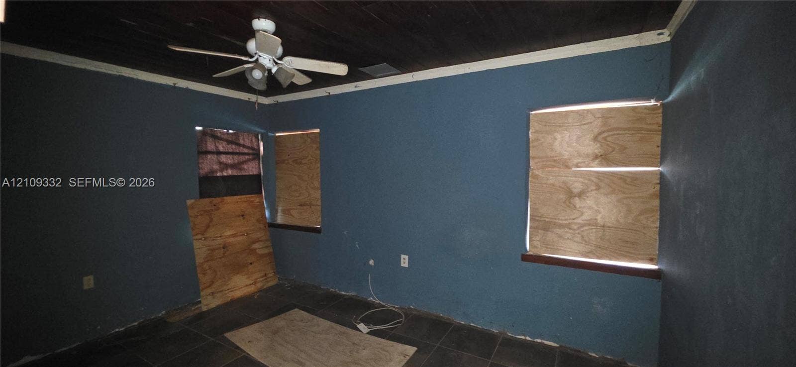 Dark-toned wood plank ceiling, dual-tone wall finish, and large-format floor tiling featuring a mounted ceiling fan
