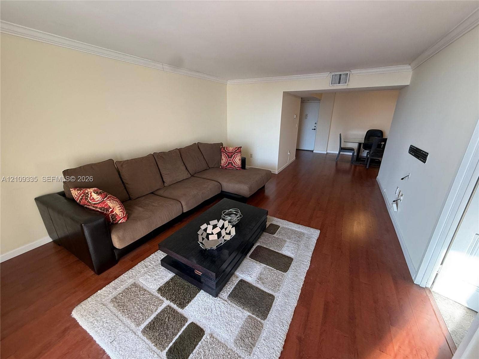 Living area featuring wood-finish flooring and crown molding