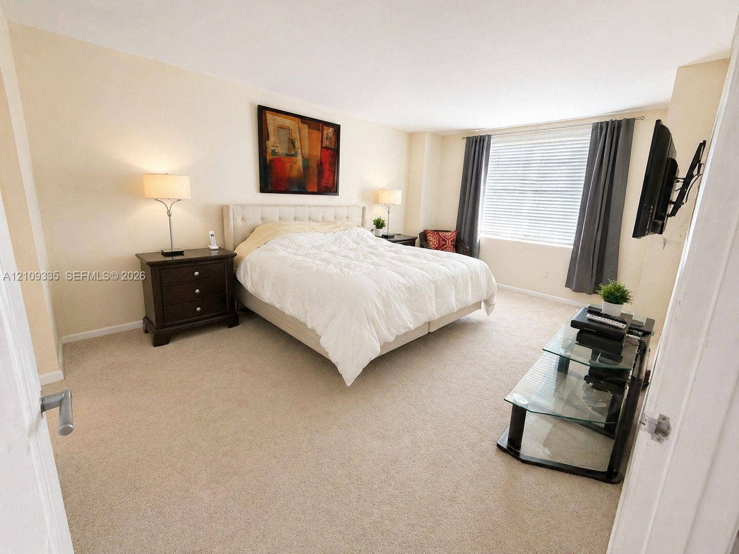 Neutral-toned interior space featuring wall-to-wall carpeting and a window with horizontal blinds