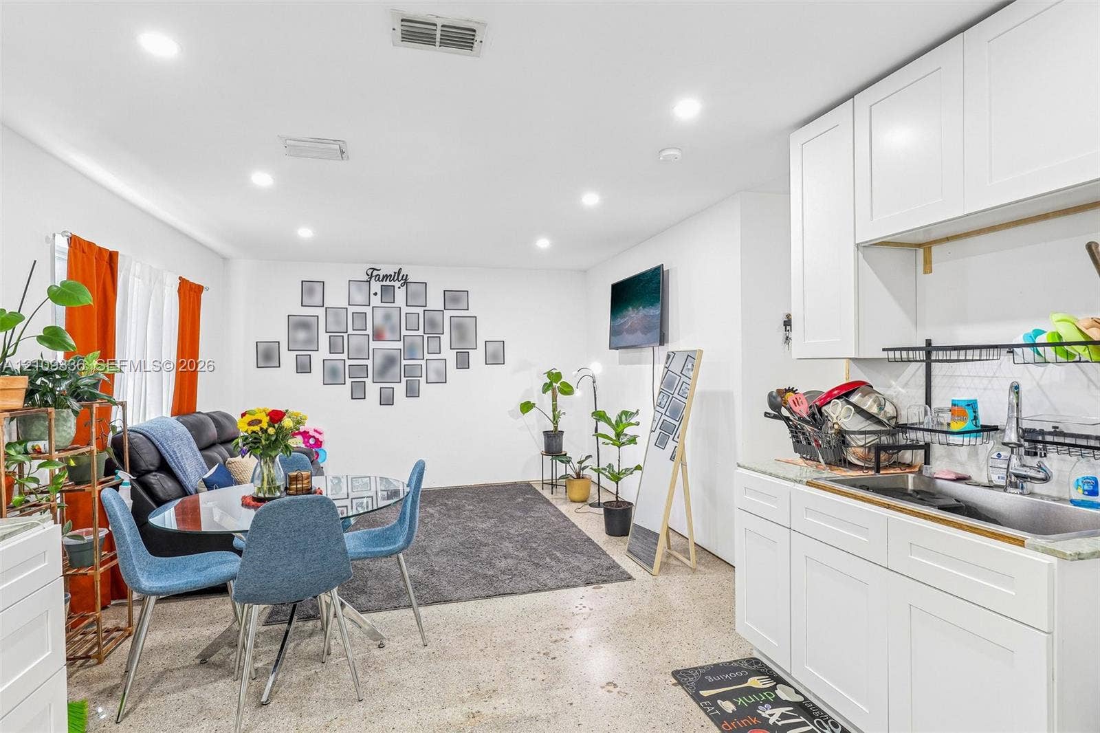 Open-concept space featuring recessed lighting, white shaker-style cabinetry, a stainless steel sink, and polished concrete flooring