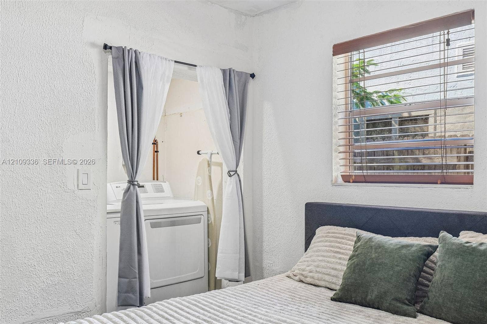 Textured walls and a recessed alcove featuring an integrated laundry hookup with washer