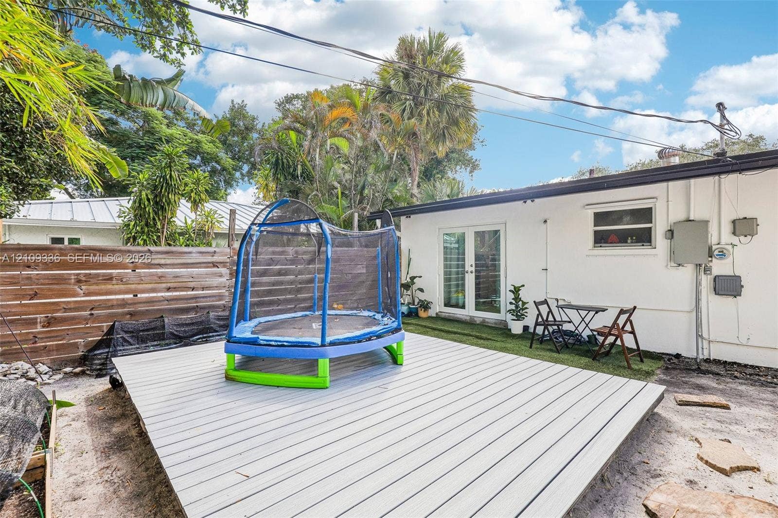 Backyard featuring a raised composite deck, horizontal wood-slat privacy fencing, and exterior French doors