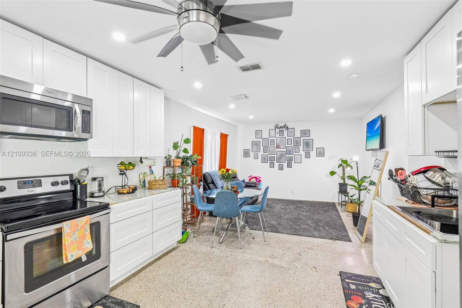 Kitchen featuring white shaker-style cabinetry, stone countertops, stainless steel appliances, recessed lighting, and a multi-blade ceiling fan