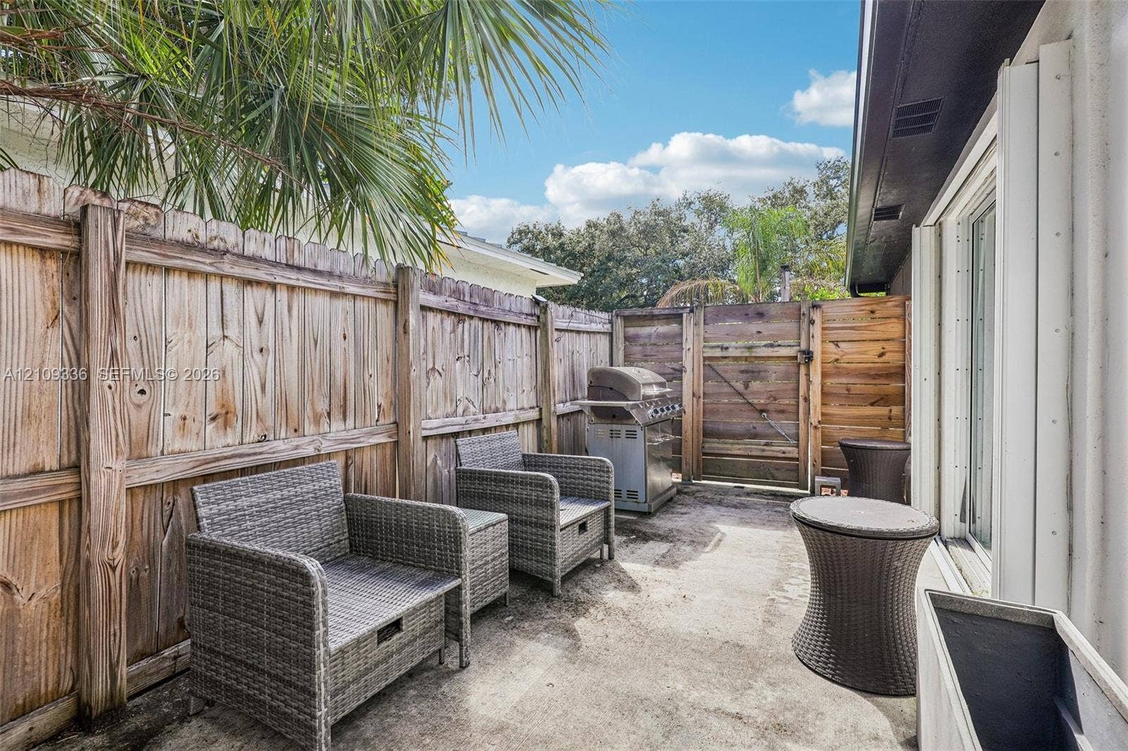 Concrete patio featuring a vertical wood-plank privacy fence and an integrated wooden access gate