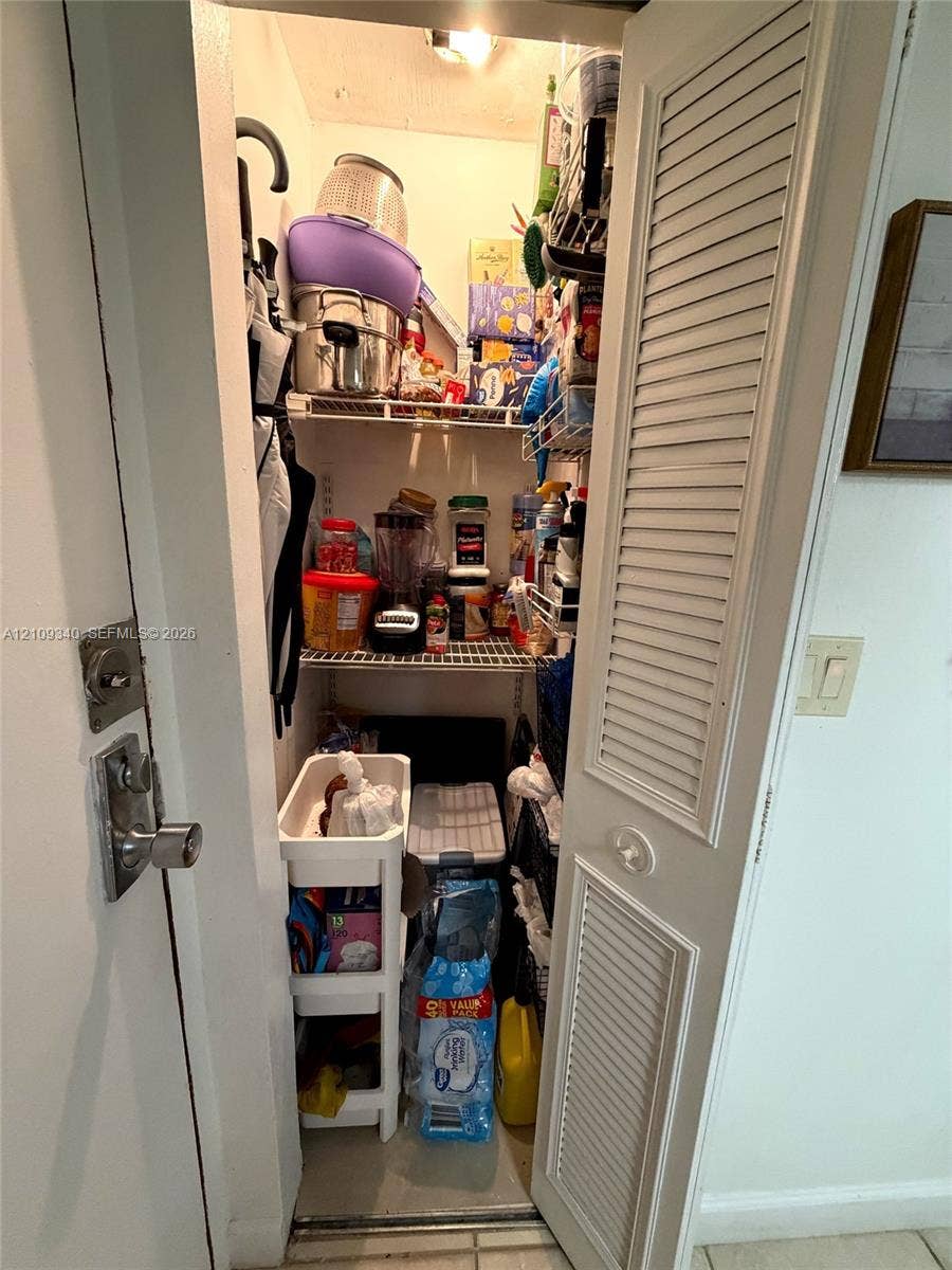 Storage closet featuring white louvered doors, white wire shelving, and overhead interior lighting