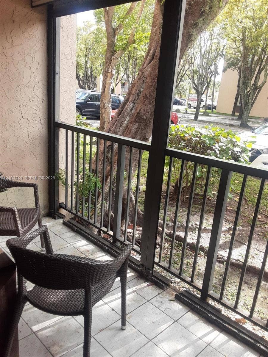 Screen-enclosed balcony with ceramic tile flooring and metal railing