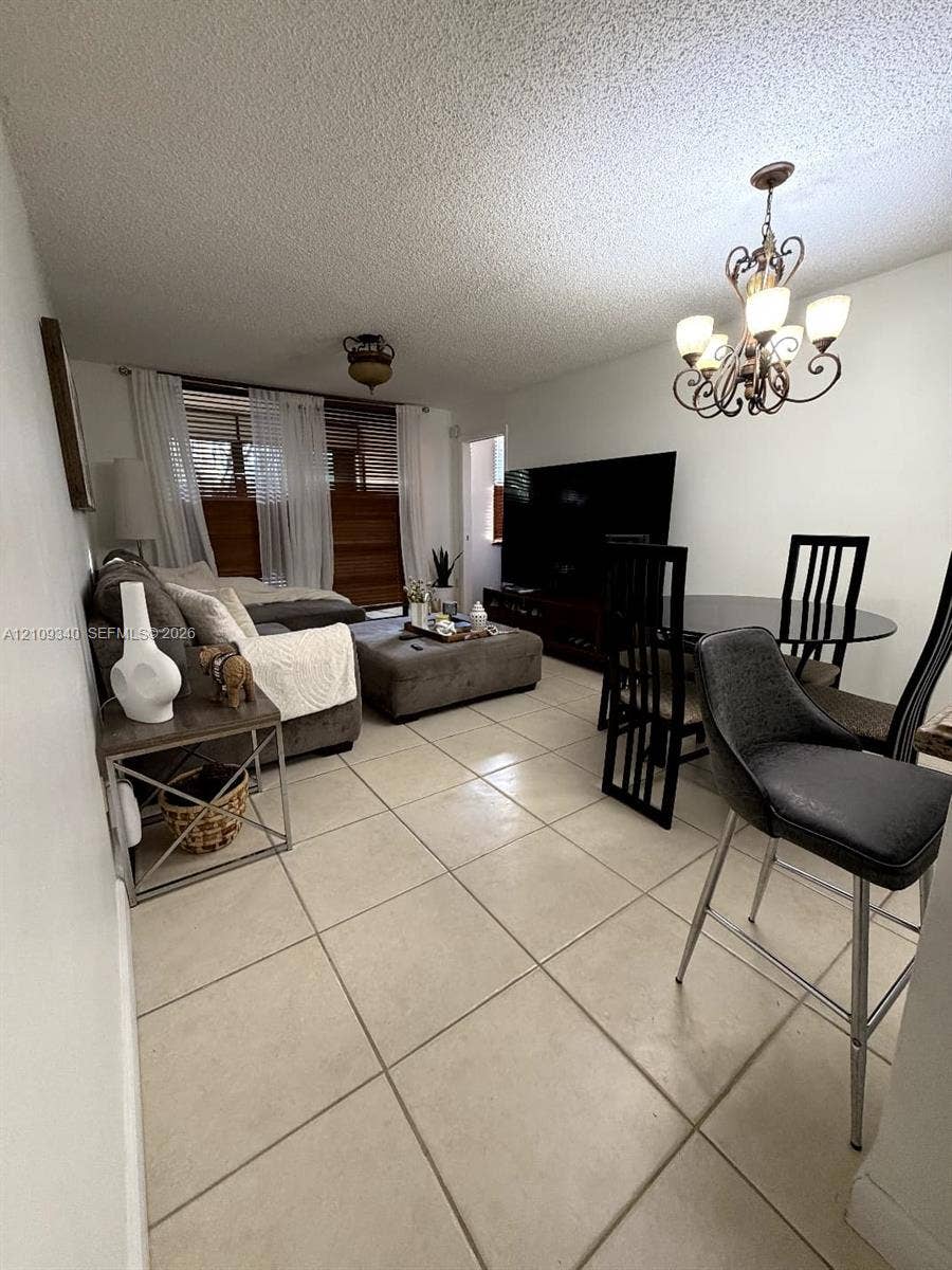 Large format tile flooring, decorative multi-arm chandelier, and sliding window treatments