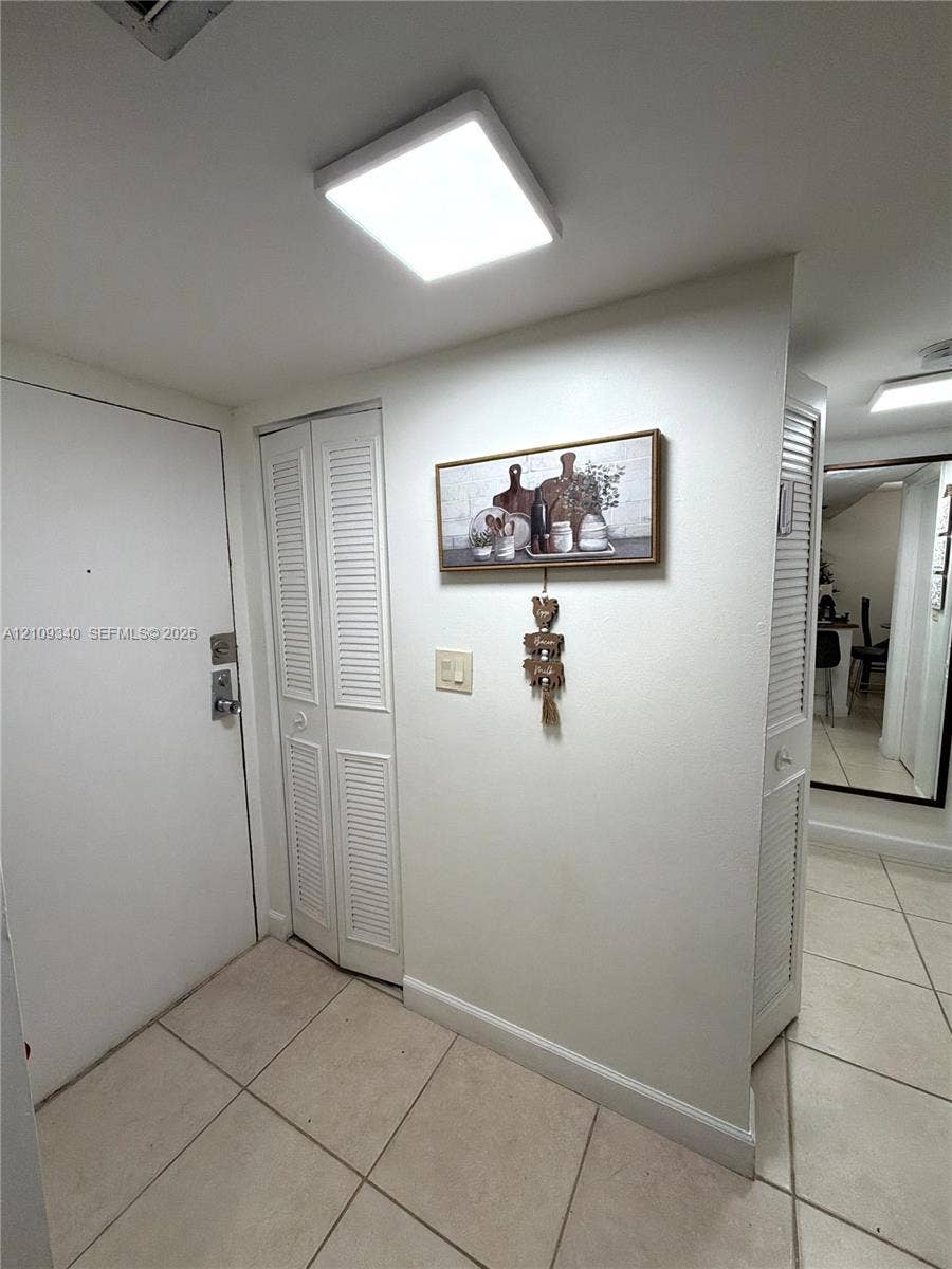 Tile flooring, square flush-mount overhead lighting, and dual louvered-panel closets