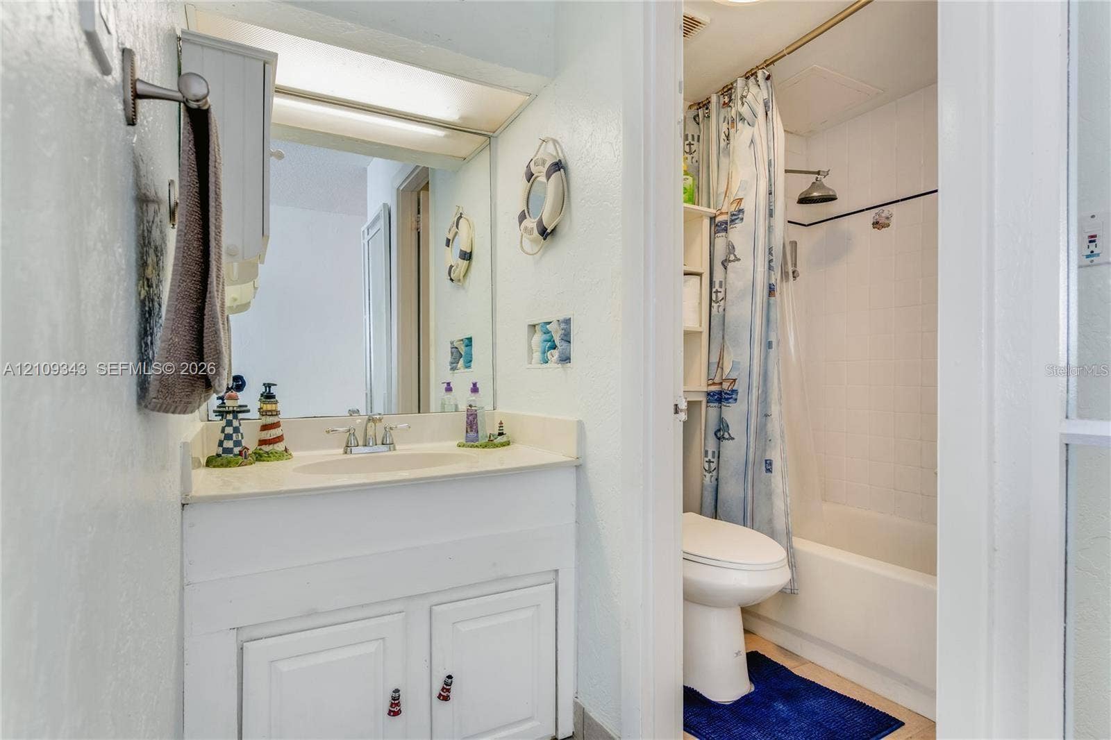 Bathroom featuring a white vanity with an integrated sink, dual-handle faucet, large wall-mounted mirror, and a tub-shower combination with a fixed showerhead