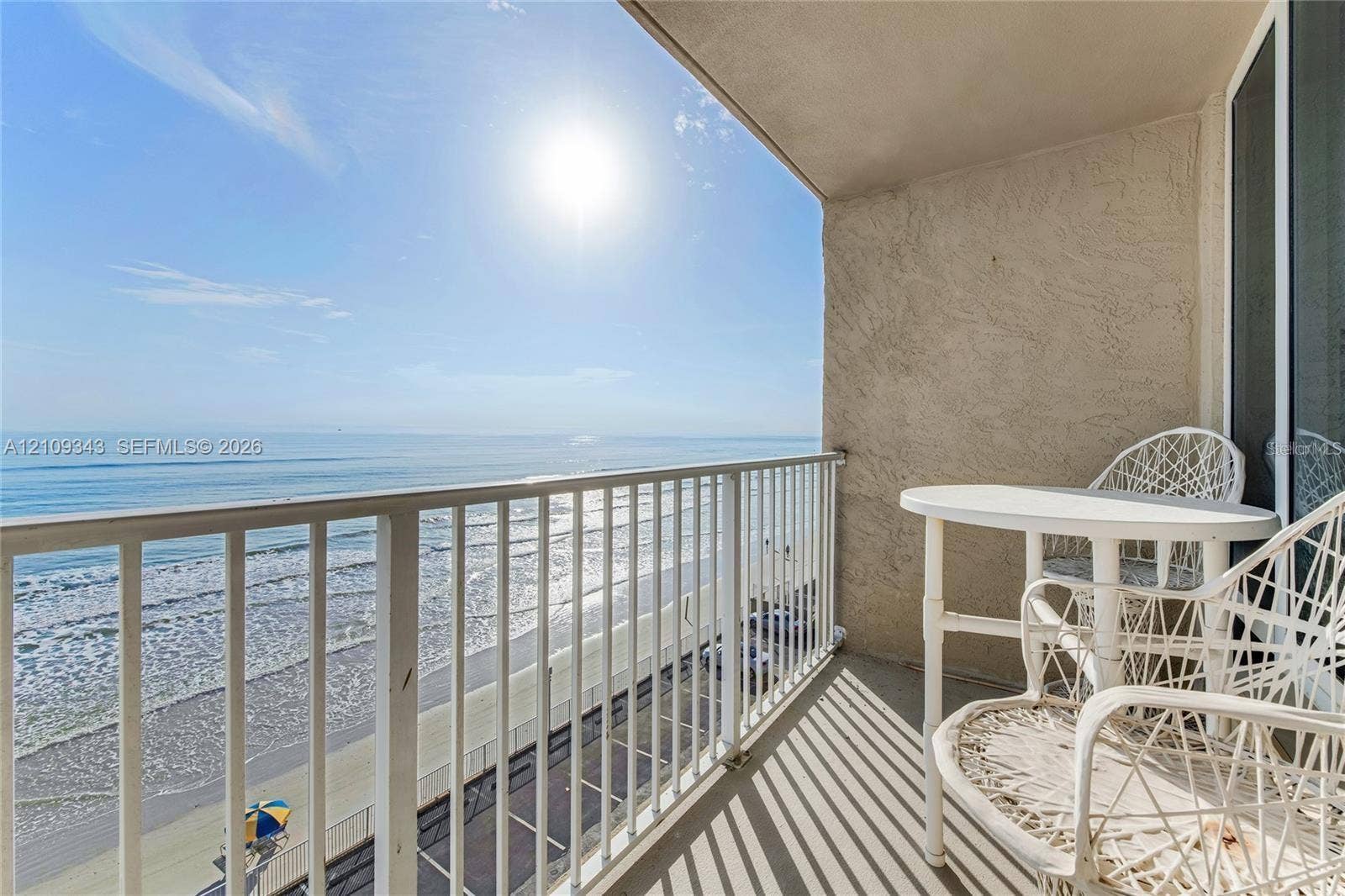 Covered balcony with white metal railings, stucco wall finishes, and direct exposure to the coastline