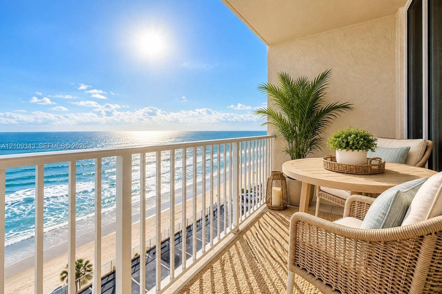 Covered balcony featuring white vertical railings and textured stucco walls, overlooking the ocean shoreline