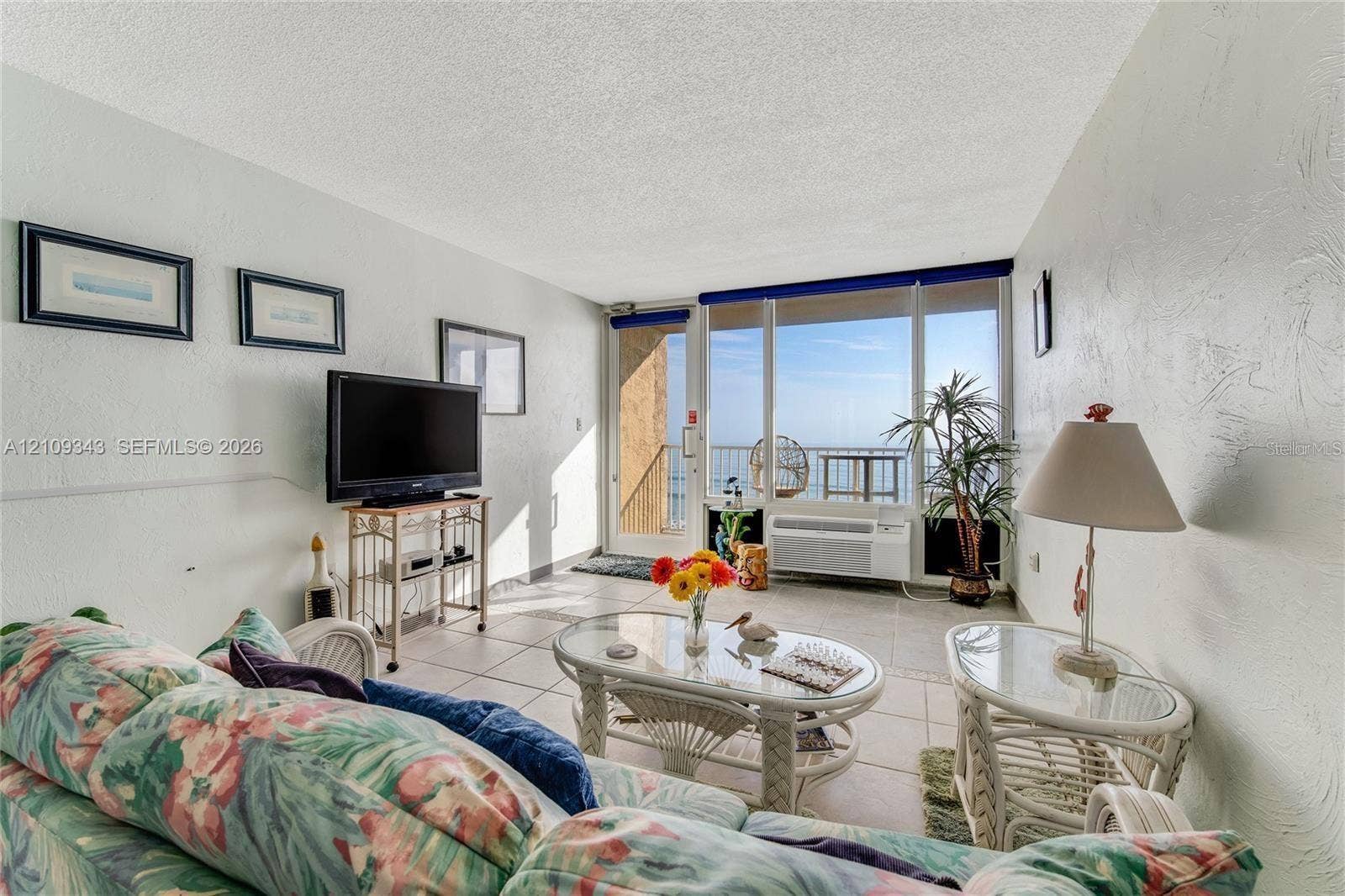 Living area featuring neutral tile flooring, expansive floor-to-ceiling windows, and access to an exterior balcony