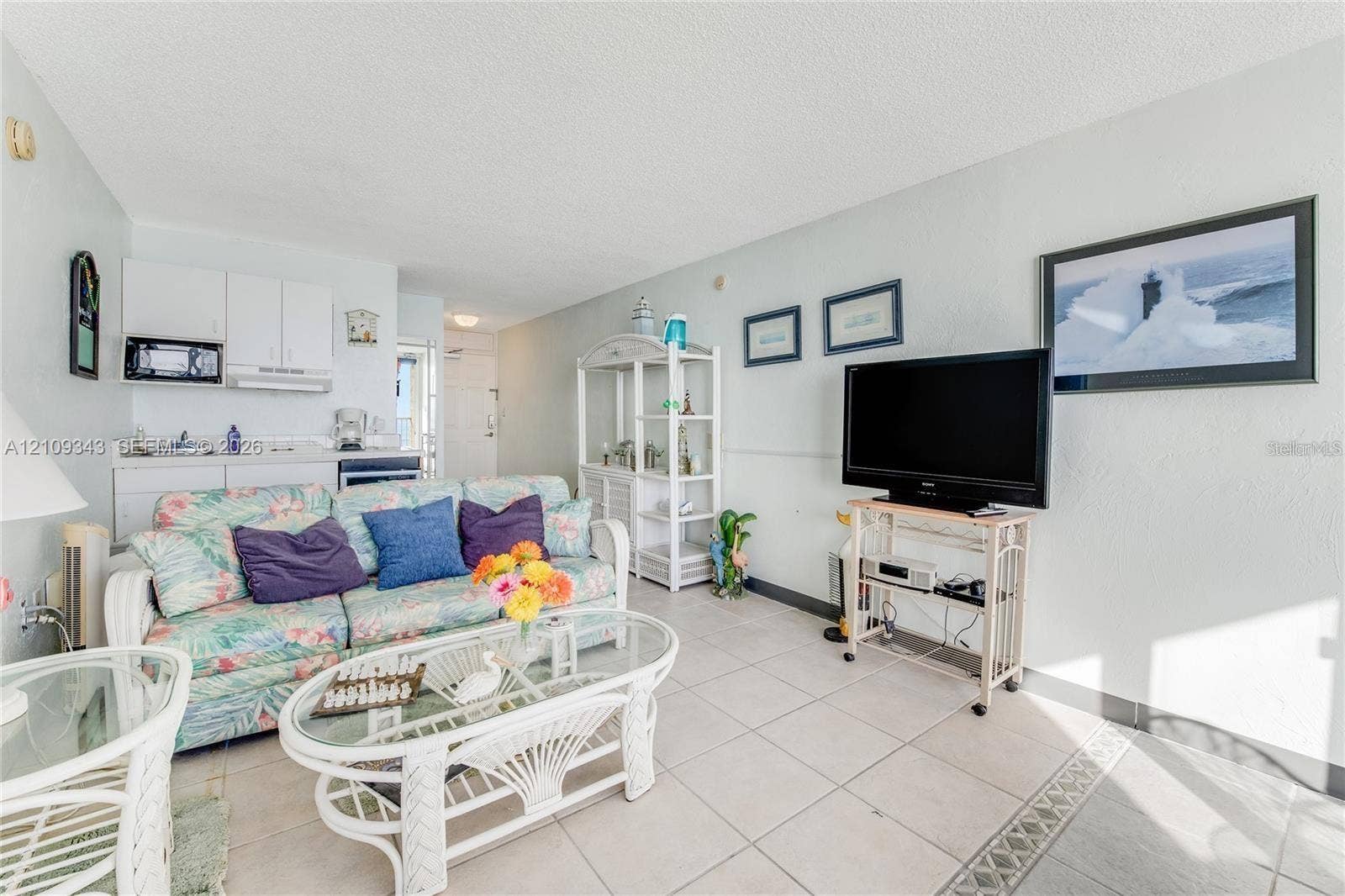 Open-concept living space featuring large-format tile flooring, white cabinetry, and a mounted over-the-range microwave