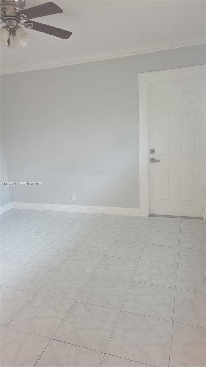 3128 SW 12th Place, #1-4, Fort Lauderdale, Fort Lauderdale, FL 33312 Neutral-toned interior space featuring tile flooring, crown molding, and a multi-paneled door with brushed metal hardware, complemented by an overhead ceiling fan with attached lighting
