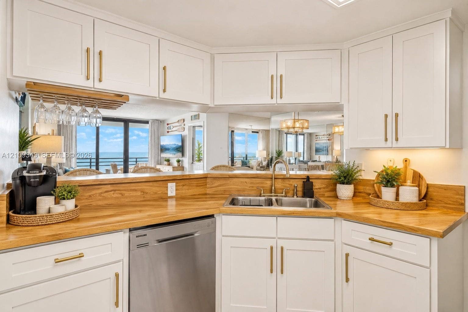 3115 S Atlantic Avenue, #G030, Daytona Beach, FL 32118 Kitchen featuring white shaker-style cabinetry, wood-finish countertops, brass-toned hardware, a stainless steel dishwasher, and a dual-basin stainless steel sink
